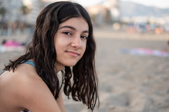 12-year-old teenage girl on the beach with her towel looking at the camera