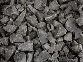A close-up view of a textured background made of small, irregularly shaped dark gray stones. 