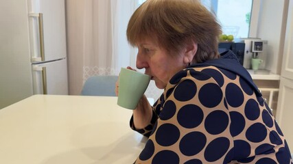 Good morning. Comfort relaxed senior old elderly woman grandmother drinking hot beverage tea coffee in kitchen at home. Mature woman resting enjoy calm morning at modern home alone. Pension concept - Powered by Adobe