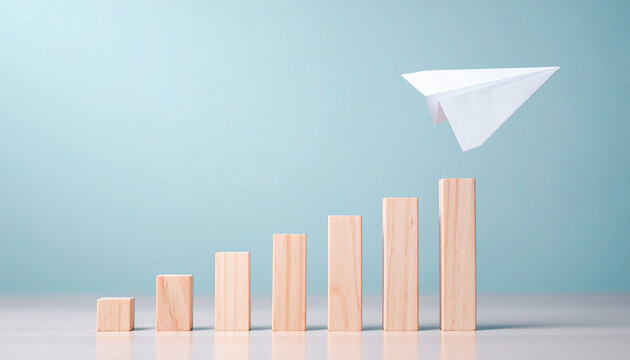 Paper airplane ascending above wooden bar graph, fast-moving progress or innovative growth.
