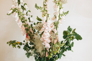 Minimalist floral arrangement with foxgloves in black vase on light table.