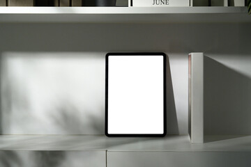 Digital tablet with empty screen propped upright on office shelf with soft shadows