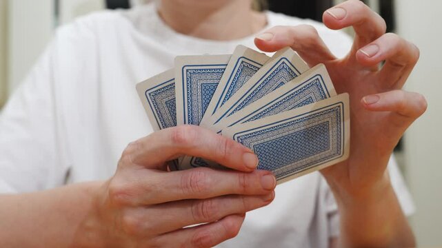 without a face. Hands of a man in a white t-shirt with cards during the game. gambling. A board game for spending leisure time with friends and family.