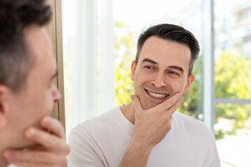 Smiling man after shaving near mirror at home