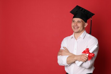 Happy student with diploma after graduation on red background. Space for text