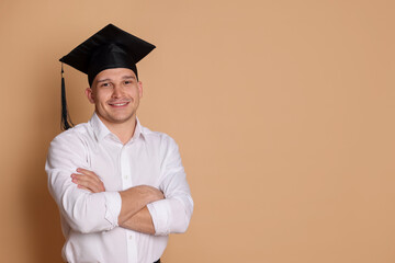 Happy student with crossed arms after graduation on beige background. Space for text