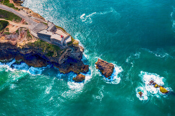 Rocky Cape with a lighthouse in the city of Nazare Portugal on the shores of the Atlantic Ocean