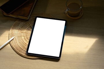 Digital tablet with blank screen on wooden desk beside coffee cup in soft morning light