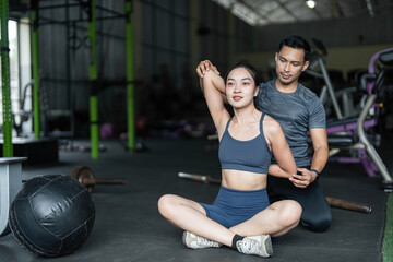Personal Training and Fitness Coaching. A trainer assisting a woman with stretching exercises in a gym.