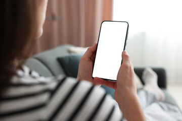 Woman using modern smartphone on sofa at home, closeup