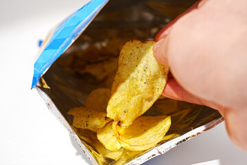 potato chips in hand. potato chips with spices in a packet. 