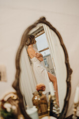 in the mirror of a beautiful young woman with blonde hair in a white dress