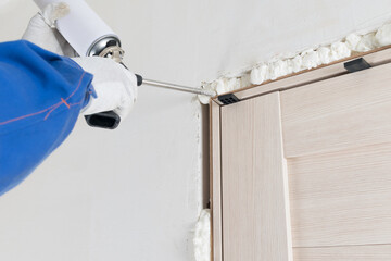 a uniformed worker installs a doorway and seals it with foam