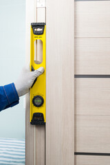 a master in a blue uniform checks the correct installation of a door in an apartment