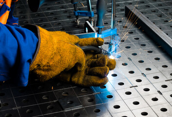 metal parts clamped in a vice, on the work table are connected by welding, bright fire