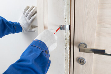 door installation technician fixes the door frame with a metal reinforcement