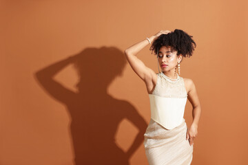 Fashionable portrait of beautiful Brazilian woman in stylish outfit on light brown background....