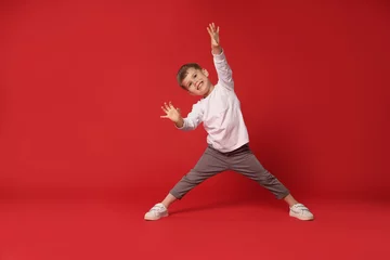 Papier peint photo Happy little boy dancing on red background, space for text