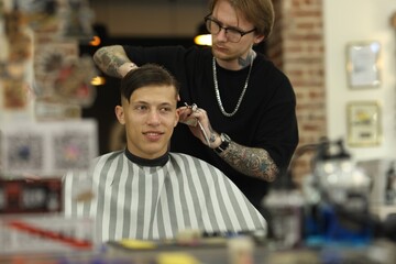 Professional barber making stylish haircut in barbershop