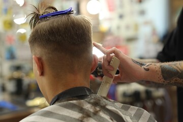 Professional barber making stylish haircut in barbershop, closeup