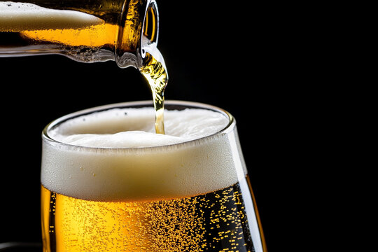 Craft beer being poured into a glass with golden hues and foam
