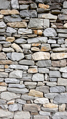 Fototapeta premium Ancient Stone Wall Texture: A detailed view of a weathered stone wall, showcasing the natural textures and patterns of the rugged building blocks, a symbol of durability and timeless beauty.