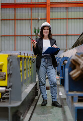 Woman engineer manager standing at steel production factory. Female inspector wears safety hard hat...