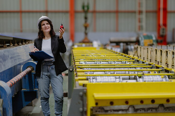 Woman engineer manager standing at steel production factory. Female inspector wears safety hard hat...