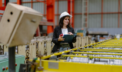 Woman engineer manager standing at steel production factory. Female inspector wears safety hard hat...