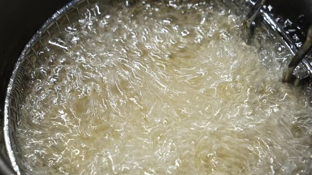Potatoes cooking into heated vegetable oil in a deep fryer. cooking in hot oil.