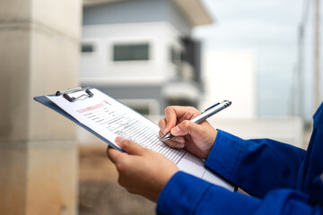 A construction foreman is checking on building quality checklist report during inspecting at the...