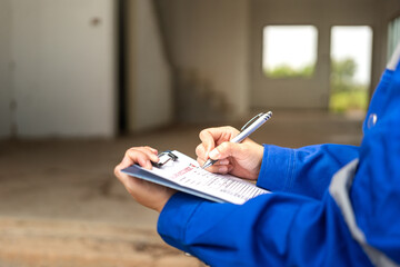 A construction foreman is checking on building quality checklist report during inspecting at the...