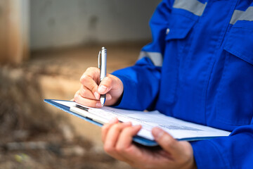 A construction foreman is checking on building quality checklist report during inspecting at the...