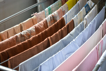 colorful clothes drying on metal rack indoors near window, symbol of home routine, laundry day,...
