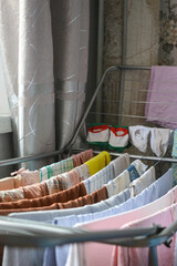 colorful clothes drying on metal rack indoors near window, symbol of home routine, laundry day,...