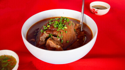 Chinese Yunnan style stewed pork in a white bowl on a red background