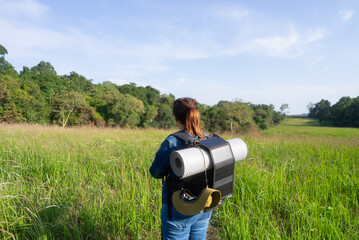 Eco-friendly hiking with solar-powered gear. Rear view of an Asian woman discovering sustainable travel, off-grid adventures, and nature exploration with low environmental impact.