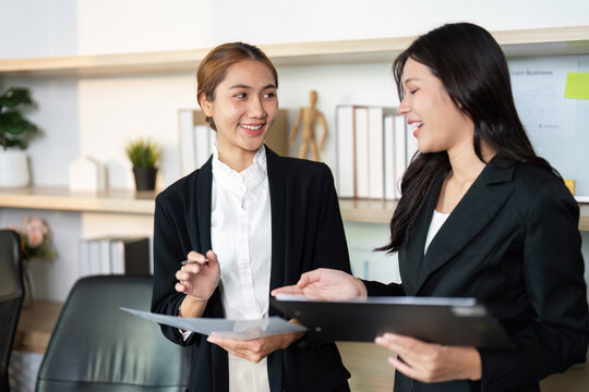 Engaging Conversation in Office. Two women exchanging ideas while reviewing documents.