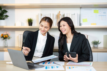 Professional Collaboration in Office. Two women discussing project data on a laptop.