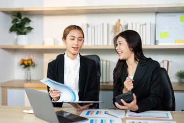 Business Meeting in Office. Two women analyzing reports and sharing insights.