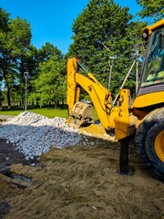 A yellow excavator is digging into the ground. The scene is outdoors and the sky is clear
