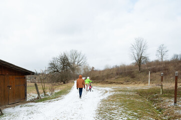 Exploring a snowy path with children in winter coats while a playful dog accompanies them near a...