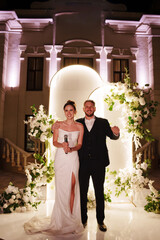 a bride and groom in front of a wedding arch decorated with flowers