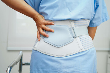 Asian woman wearing lumbar support pain back and use walker in hospital.