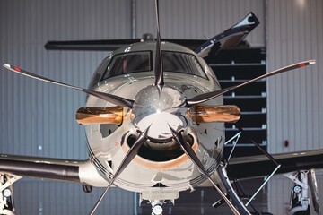 Symmetrical front view of a private turboprop aircraft in a hangar, showing polished spinner,...