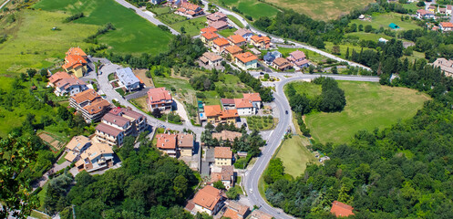 Scenic view of a quaint village in Italy surrounded by lush green hills on a sunny day