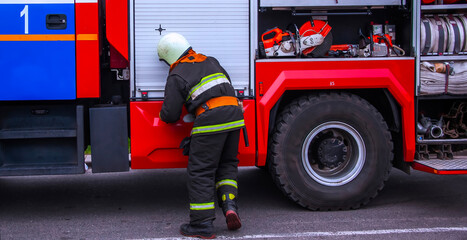 Firefighter preparing equipment at an emergency response scene in a city during daytime