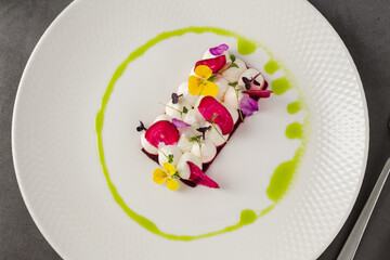 Colorful beetroot slices with goat cheese, garnished with edible flowers