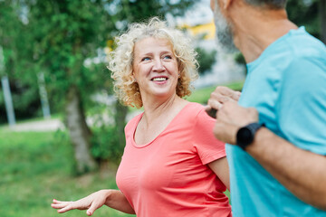 Smiling active mature mid aged couple jogging exercising and having fun and laughing together...
