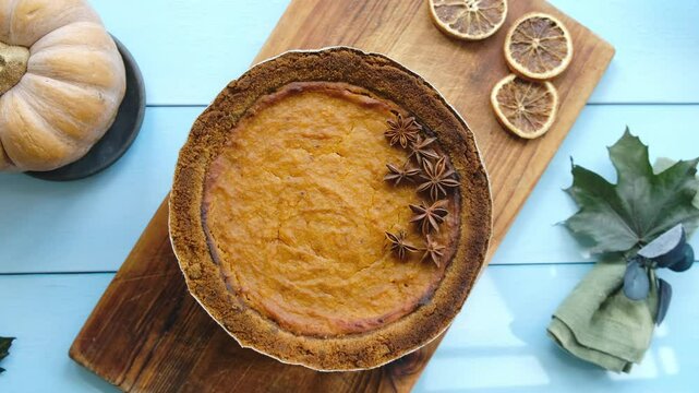 Hands placing cooked pumpkin pie on table for Thanksgiving